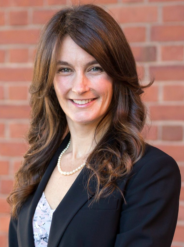 Woman smiling in front of brick wall.