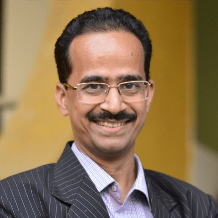 Smiling man wearing glasses and suit.