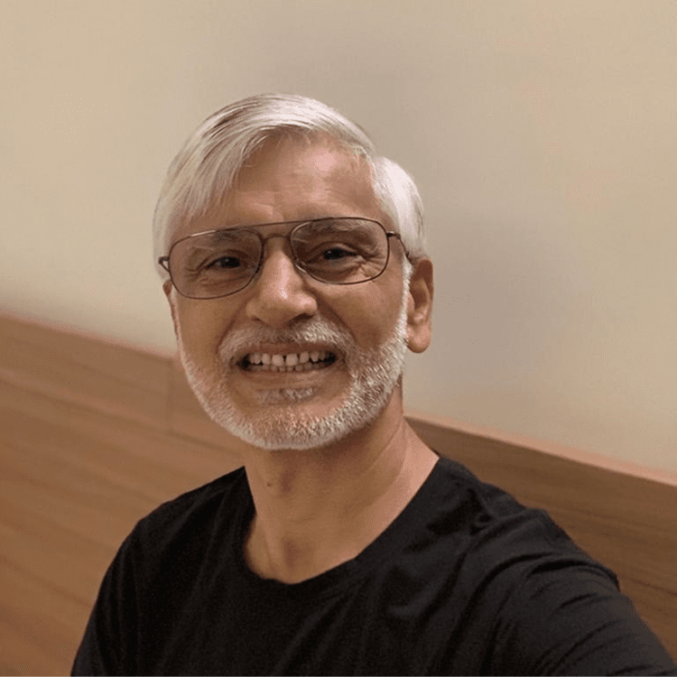 Smiling man with glasses and white beard.
