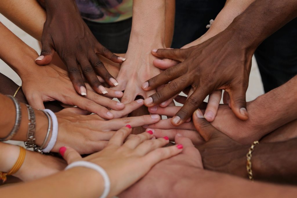 Diverse hands together in unity circle.