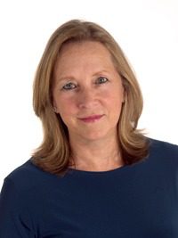 Woman in blue shirt, smiling at camera.