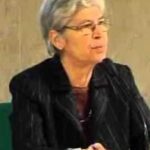 Elderly woman speaking at an event.