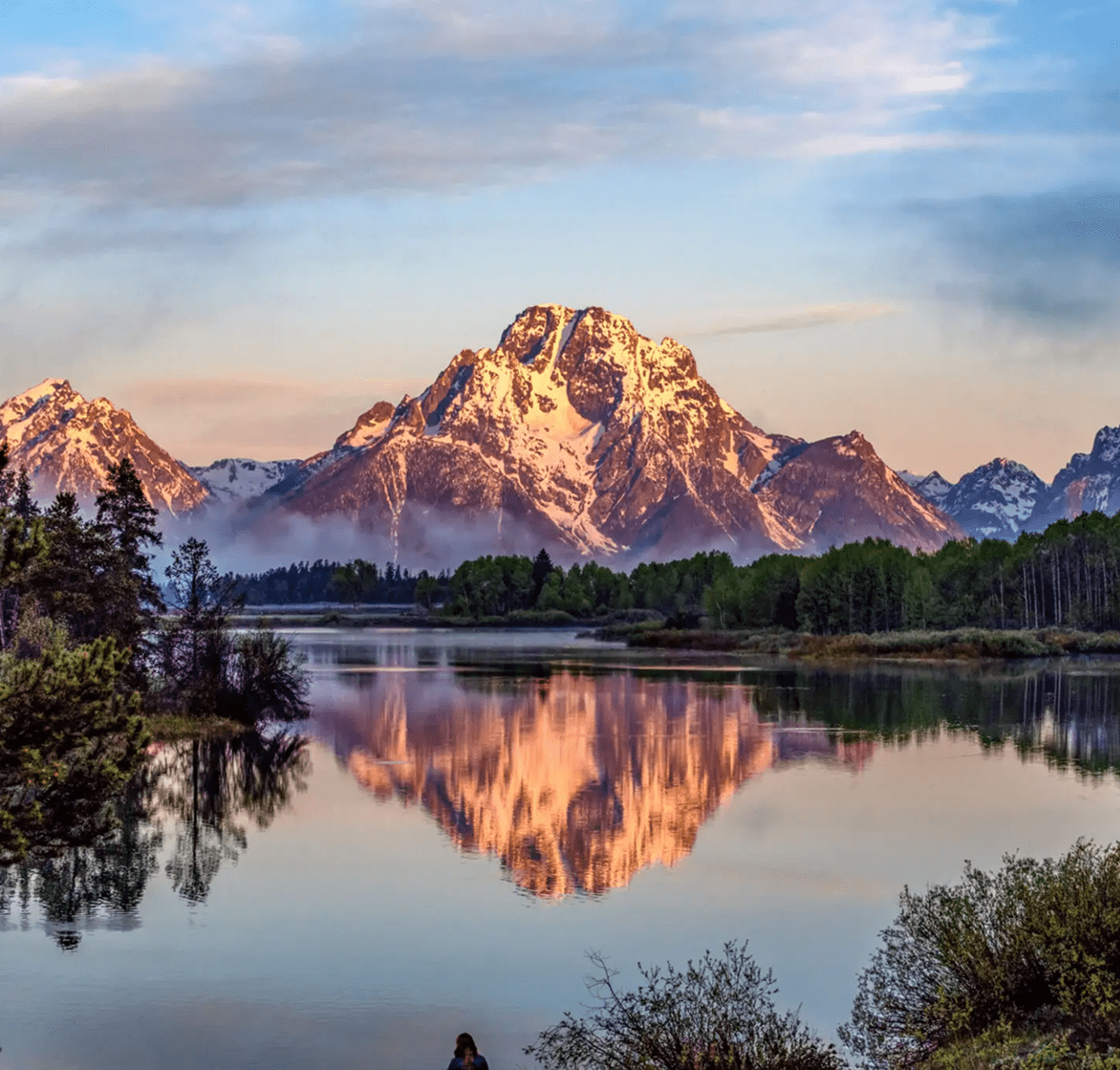 Mountain peaks reflecting in a calm lake at sunset.