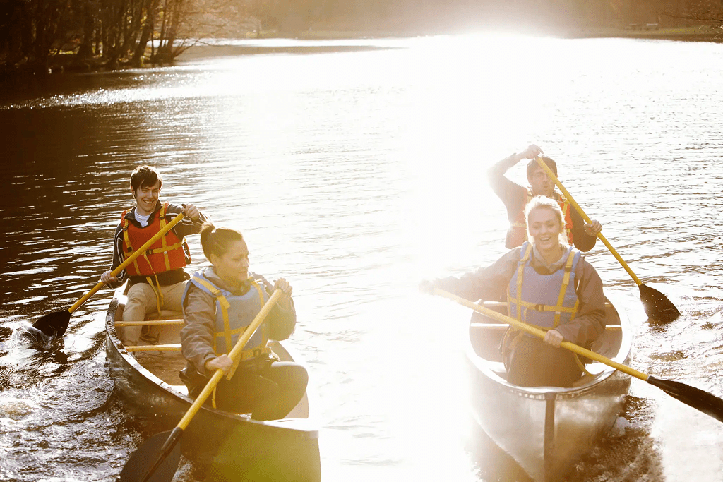 People canoeing on a sunlit lake in the late afternoon.