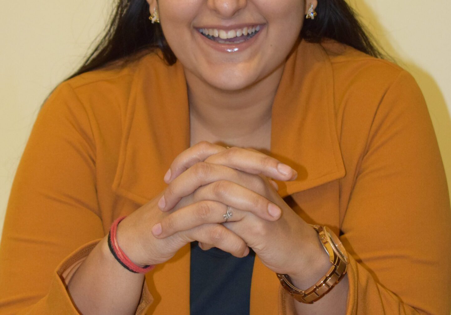 Smiling person in orange outfit, seated indoors.