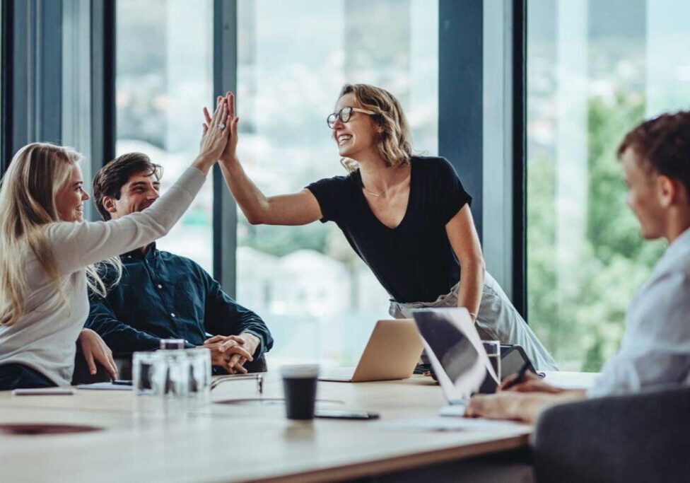 Two colleagues celebrating a success with a high-five in a modern office.