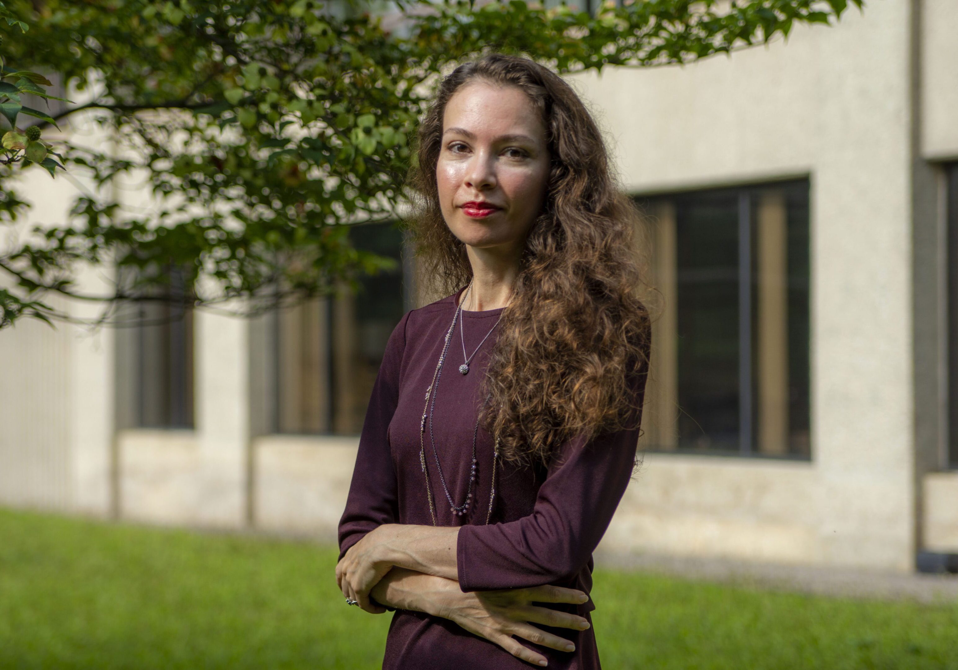 Woman standing outside near building and trees.