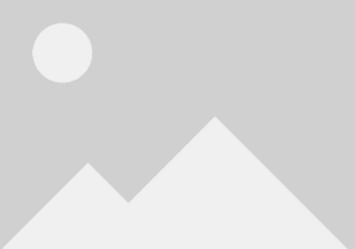 A man sitting on a wooden bench with a dog beside him outdoors.