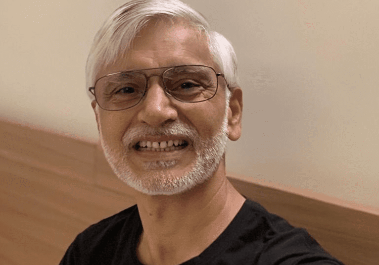 Smiling man with glasses and white beard.