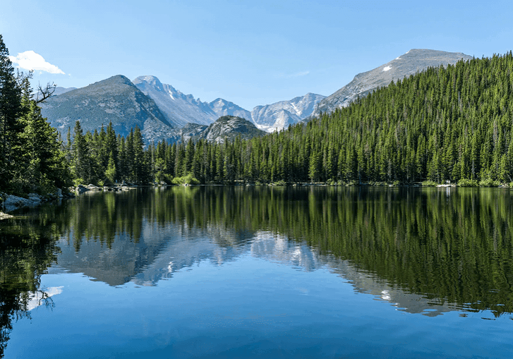 Calm mountain lake with clear reflections under a blue sky.