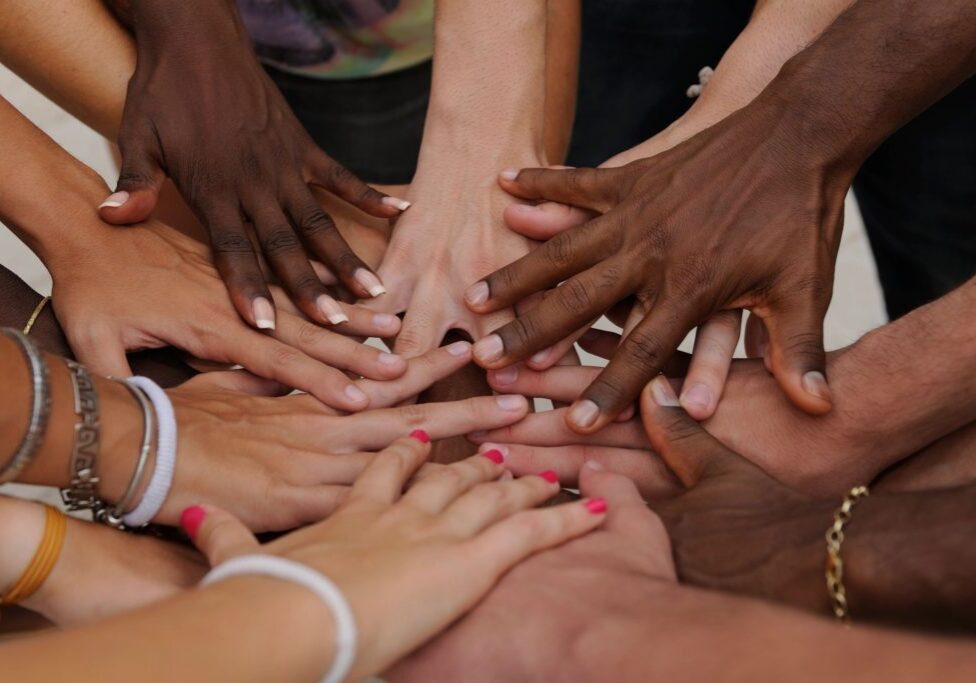 Diverse hands together in unity circle.
