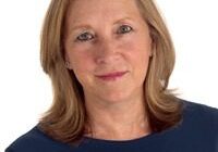 Woman in blue shirt, smiling at camera.