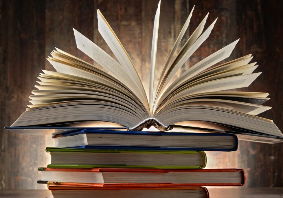 Open book on stack of colorful books.